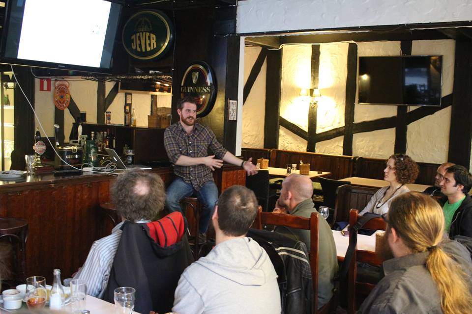 Glen Wright presenting Academia Obscura in a pub, with slides on screen